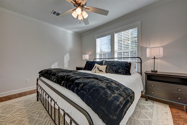 bedroom featuring baseboards, crown molding, wood finished floors, and a ceiling fan