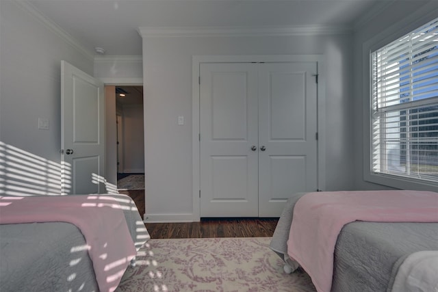 bedroom featuring dark hardwood / wood-style flooring, ornamental molding, and a closet