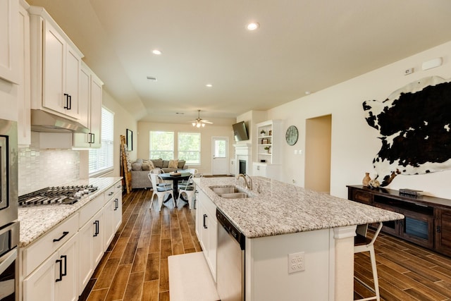 kitchen with a kitchen island with sink, sink, appliances with stainless steel finishes, dark hardwood / wood-style flooring, and white cabinetry