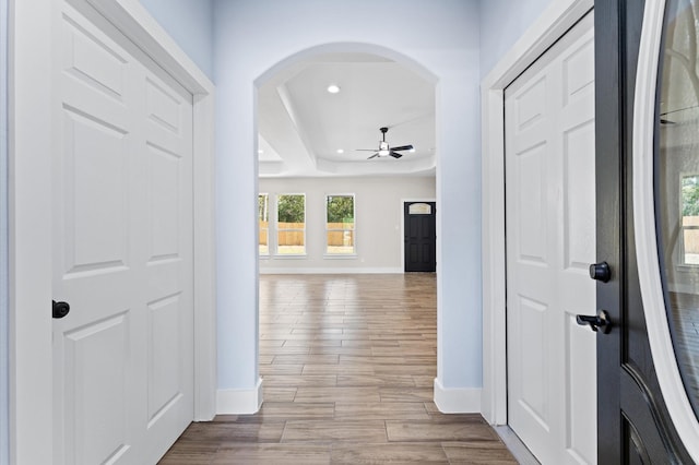 corridor featuring a tray ceiling and light hardwood / wood-style flooring