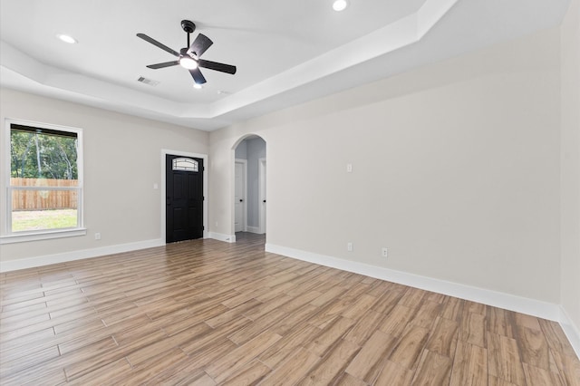 unfurnished room featuring ceiling fan, a tray ceiling, and light hardwood / wood-style flooring