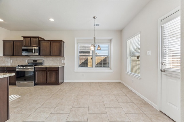 kitchen featuring hanging light fixtures, stainless steel appliances, an inviting chandelier, dark brown cabinets, and light tile patterned floors