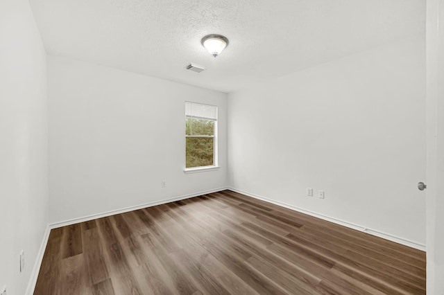 empty room with dark hardwood / wood-style flooring and a textured ceiling