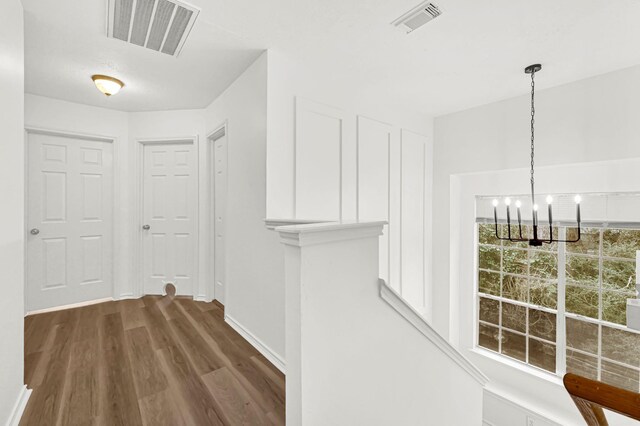 hall featuring dark wood-type flooring and a chandelier