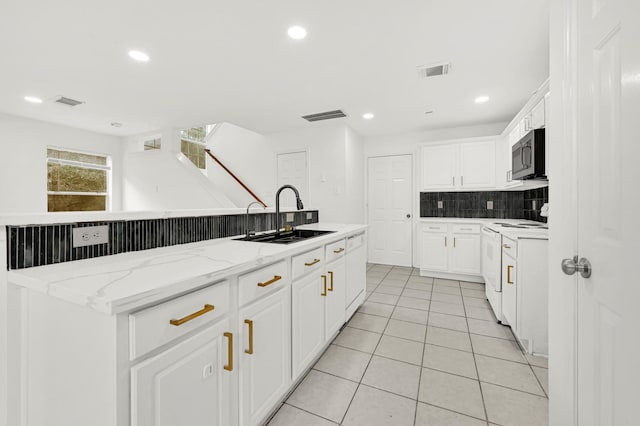 kitchen with white cabinets, white appliances, sink, and an island with sink