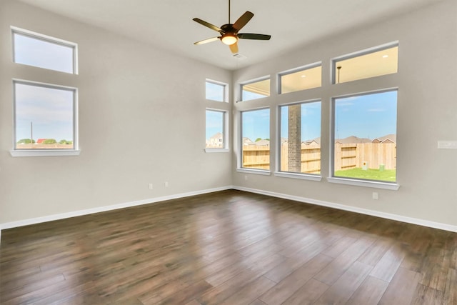 spare room featuring ceiling fan, plenty of natural light, and dark wood-type flooring