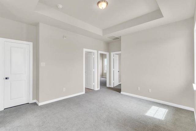 unfurnished bedroom with carpet and a tray ceiling