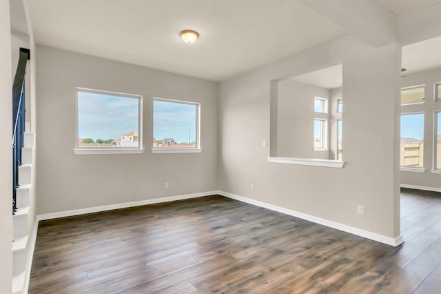 empty room featuring a healthy amount of sunlight and dark hardwood / wood-style floors