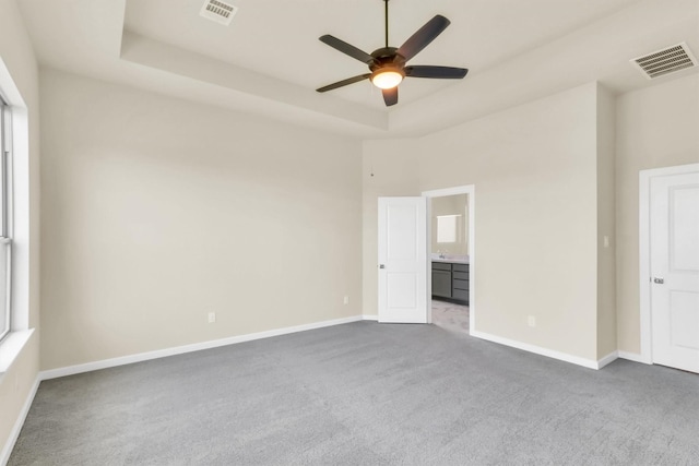 carpeted spare room with a high ceiling, a raised ceiling, and ceiling fan