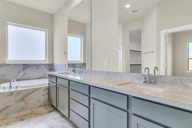 bathroom featuring vanity, tiled tub, and a wealth of natural light