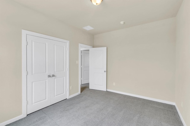 unfurnished bedroom with light colored carpet and a closet