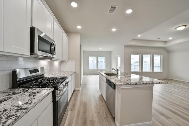 kitchen with a center island with sink, a healthy amount of sunlight, sink, and appliances with stainless steel finishes