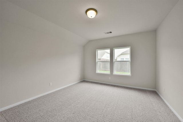 carpeted spare room featuring vaulted ceiling