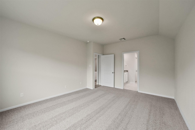 unfurnished room with light colored carpet and vaulted ceiling