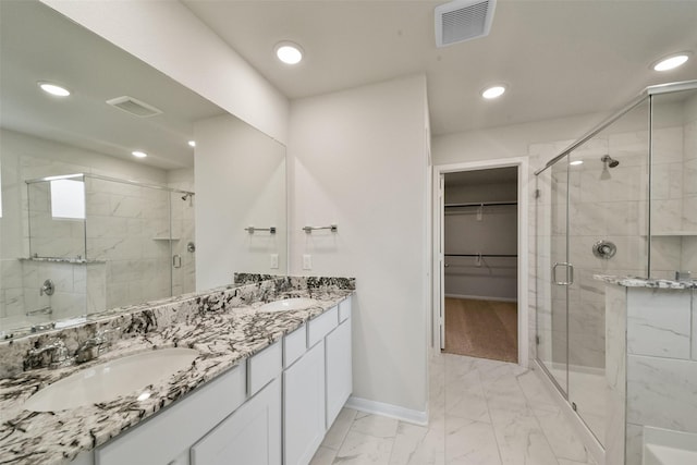 bathroom featuring a shower with door and vanity