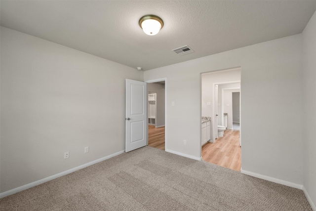 unfurnished bedroom with light colored carpet and a textured ceiling