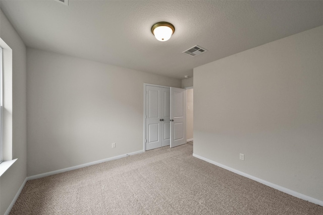 unfurnished room with light carpet and a textured ceiling