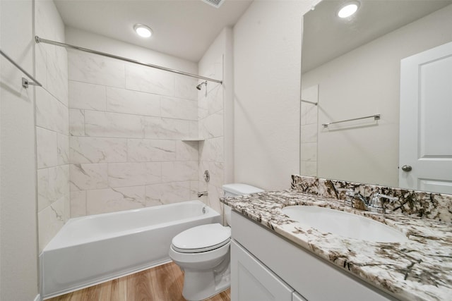 full bathroom featuring toilet, vanity, wood-type flooring, and tiled shower / bath