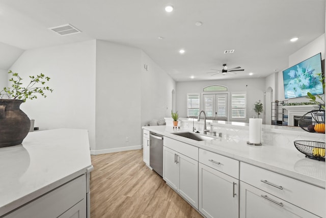 kitchen featuring stainless steel dishwasher, ceiling fan, sink, light hardwood / wood-style flooring, and white cabinetry