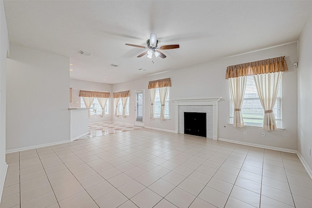 unfurnished living room with a fireplace, ceiling fan, plenty of natural light, and light tile patterned floors