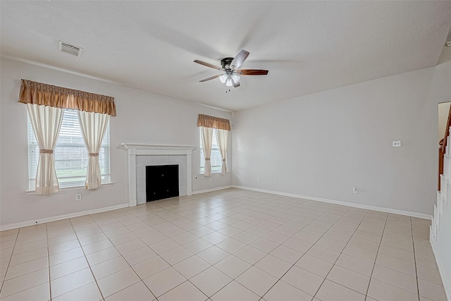 unfurnished living room with a tile fireplace, light tile patterned floors, and ceiling fan