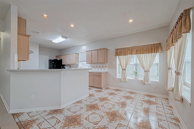 kitchen featuring black refrigerator, light brown cabinetry, kitchen peninsula, tasteful backsplash, and light tile patterned flooring