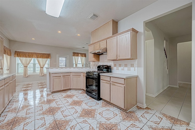 kitchen with black range oven, backsplash, kitchen peninsula, light brown cabinetry, and light tile patterned floors