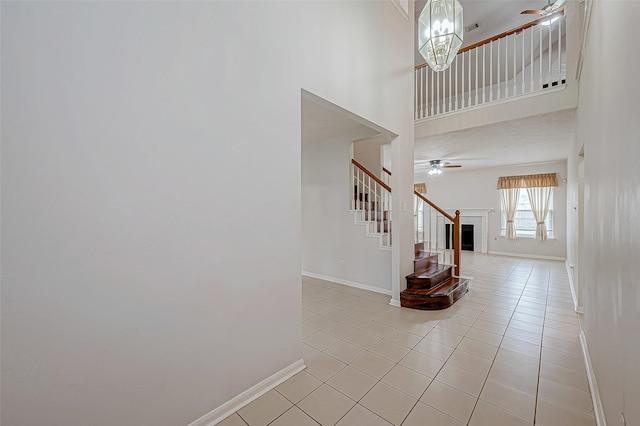 tiled foyer featuring a high ceiling and ceiling fan with notable chandelier