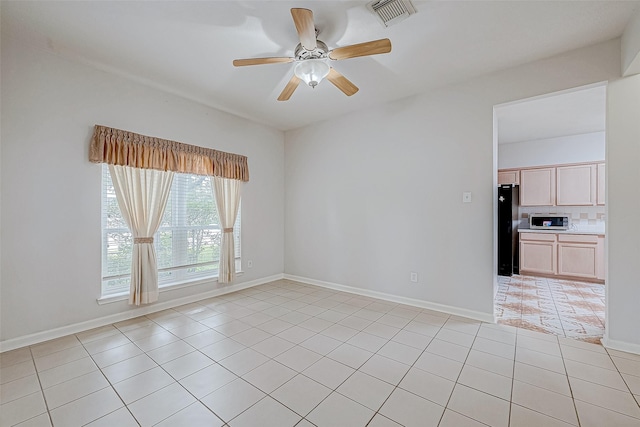 spare room with ceiling fan and light tile patterned floors