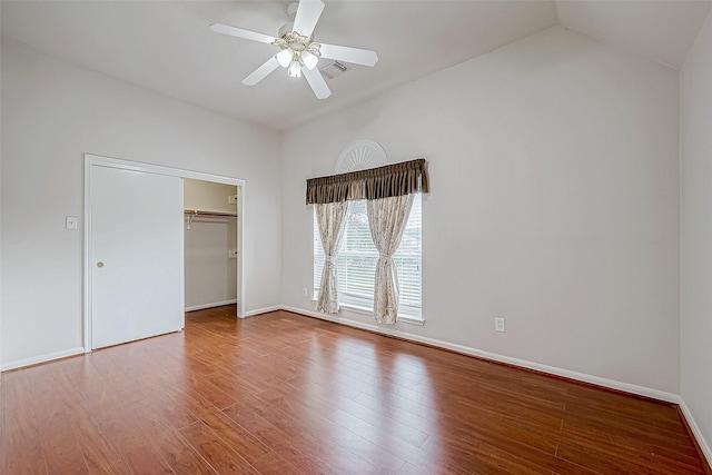 unfurnished bedroom with ceiling fan, a closet, wood-type flooring, and lofted ceiling