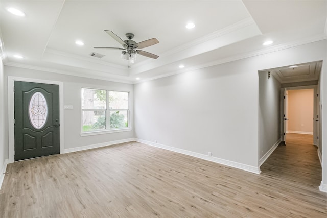 foyer with light hardwood / wood-style floors, a raised ceiling, and crown molding