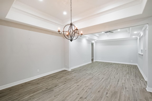 interior space with hardwood / wood-style floors, ceiling fan with notable chandelier, a tray ceiling, and ornamental molding