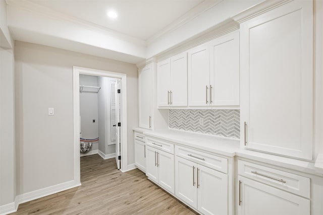 hallway with light wood-type flooring and ornamental molding