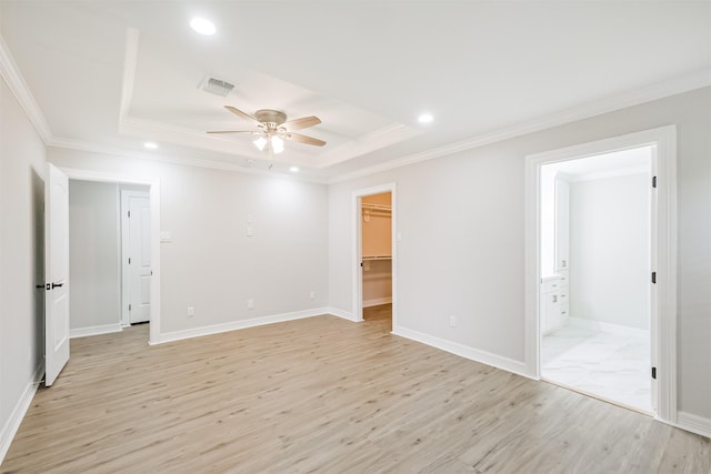 spare room with ceiling fan, light wood-type flooring, crown molding, and a tray ceiling