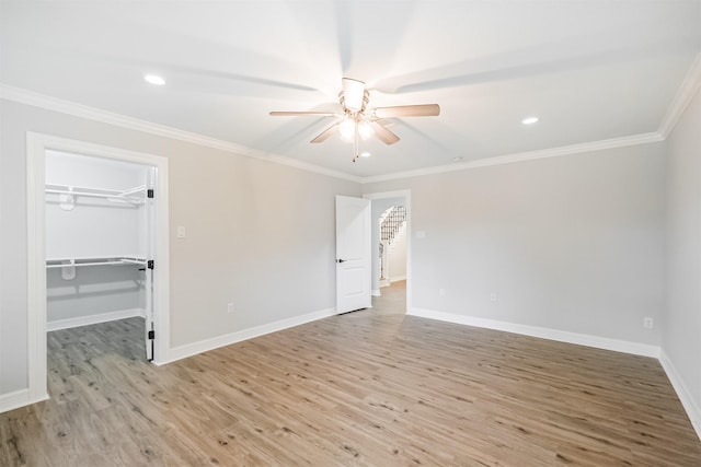 unfurnished bedroom featuring crown molding, ceiling fan, a spacious closet, light hardwood / wood-style floors, and a closet