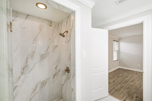 bathroom with a tile shower, wood-type flooring, and ornamental molding