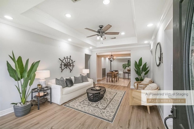 living room featuring ornamental molding, hardwood / wood-style flooring, and a tray ceiling