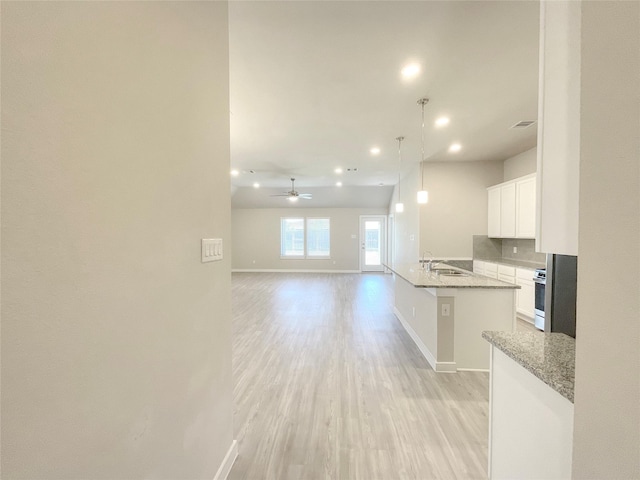 kitchen featuring white cabinets, light hardwood / wood-style flooring, ceiling fan, light stone countertops, and kitchen peninsula