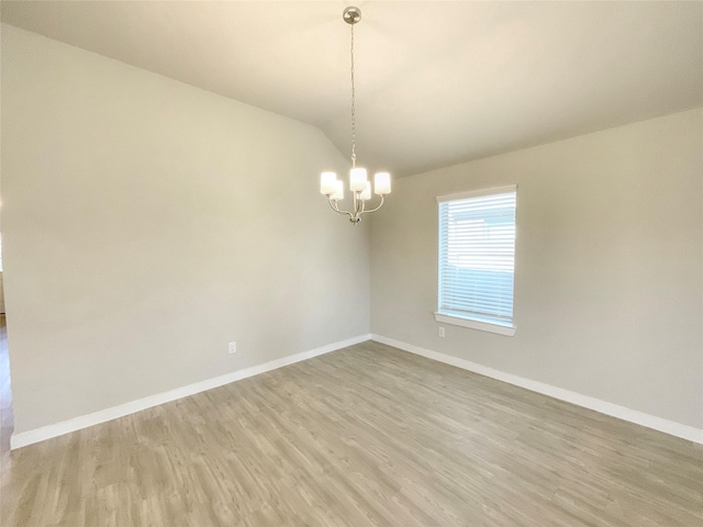 spare room with light hardwood / wood-style flooring and a notable chandelier