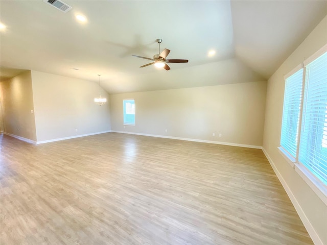 unfurnished room with ceiling fan with notable chandelier, vaulted ceiling, and light wood-type flooring