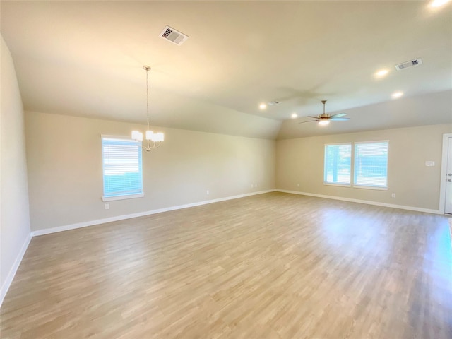 unfurnished room with lofted ceiling, ceiling fan with notable chandelier, and light wood-type flooring