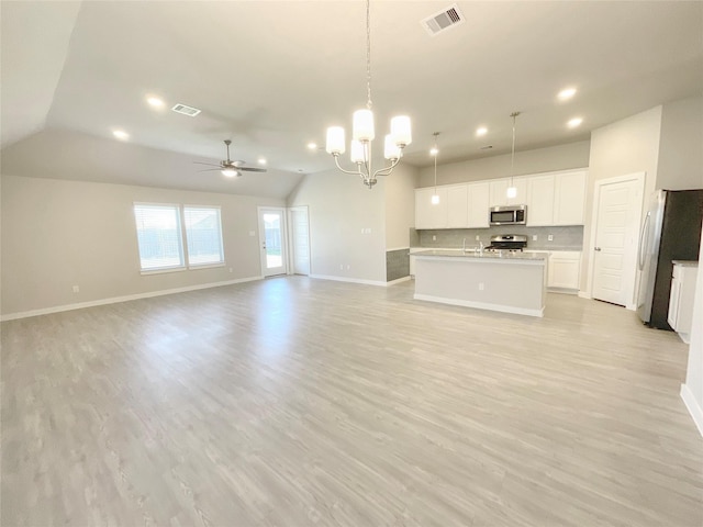 unfurnished living room featuring ceiling fan with notable chandelier, light hardwood / wood-style floors, and vaulted ceiling