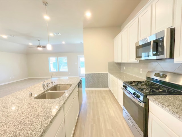 kitchen with light stone counters, sink, white cabinets, and stainless steel appliances