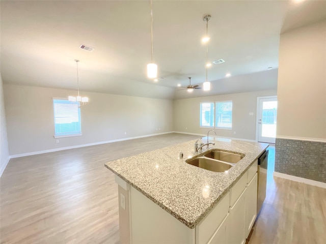 kitchen with pendant lighting, white cabinetry, sink, and a kitchen island with sink