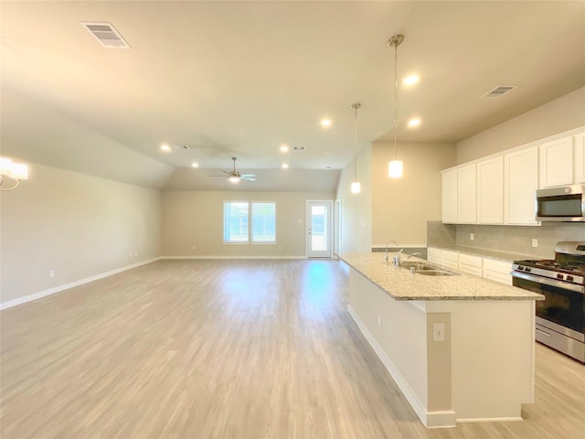 kitchen featuring light stone countertops, stainless steel appliances, sink, white cabinetry, and hanging light fixtures