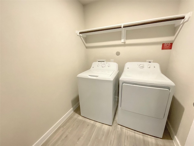 clothes washing area with light wood-type flooring and washing machine and clothes dryer