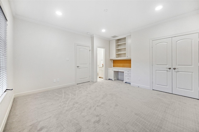 unfurnished bedroom with ornamental molding, light carpet, built in desk, and a closet