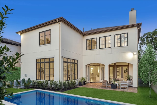 back of house with an outdoor living space, a patio area, and a yard