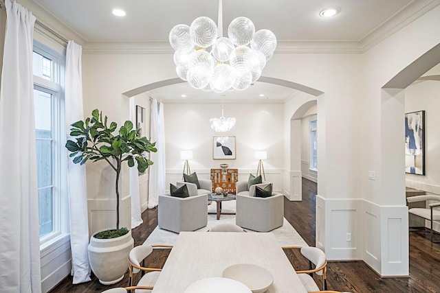 dining area with dark wood-type flooring, ornamental molding, and a chandelier