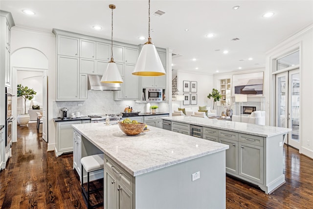 kitchen with dark wood-type flooring, a kitchen island, extractor fan, and decorative light fixtures